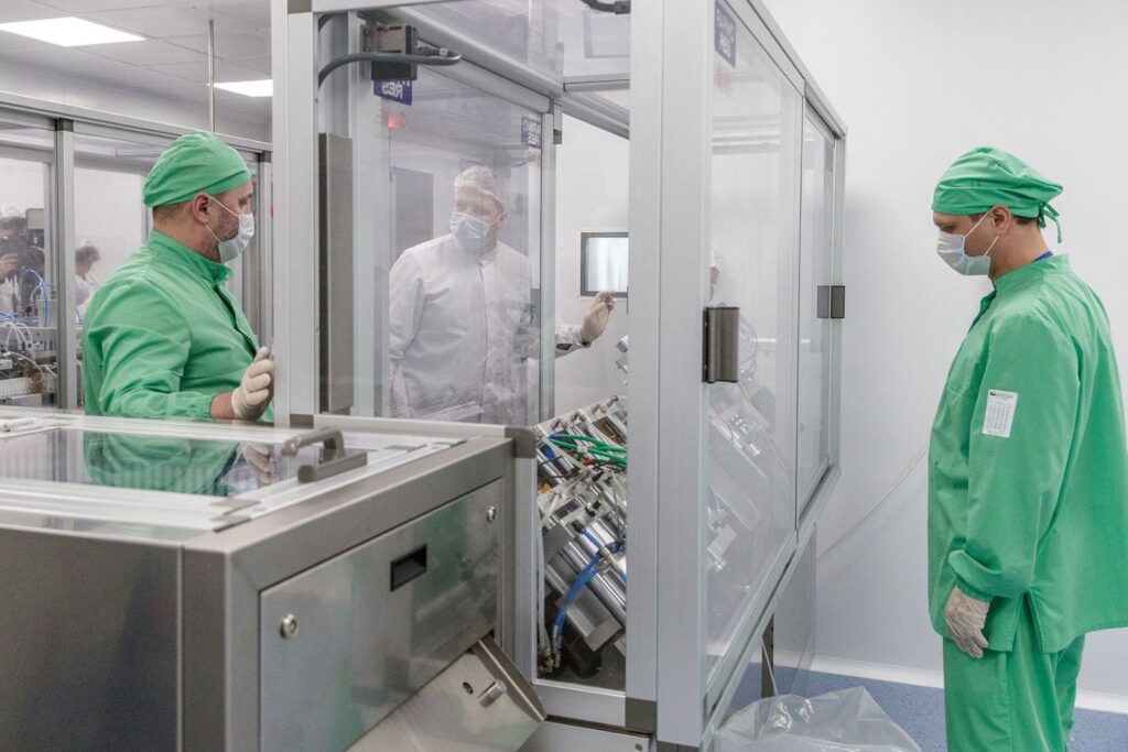 Cleanroom pharmaceutical manufacturing technicians operating precision equipment in a sterile production facility