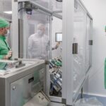 Cleanroom pharmaceutical manufacturing technicians operating precision equipment in a sterile production facility