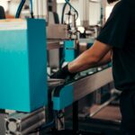 Factory worker assembling precision metal components on industrial machinery