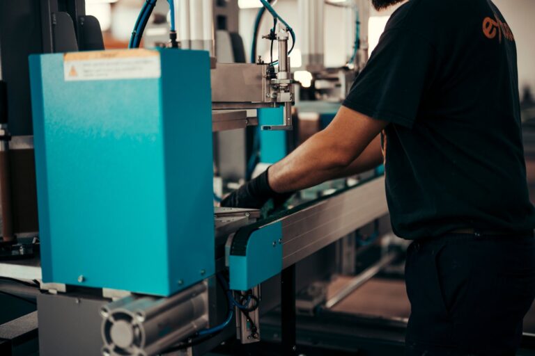 Factory worker assembling precision metal components on industrial machinery