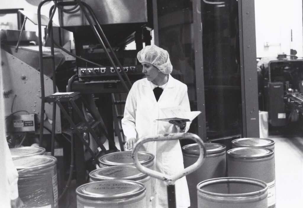 Pharmaceutical active ingredient manufacturing facility with technicians monitoring stainless steel production equipment