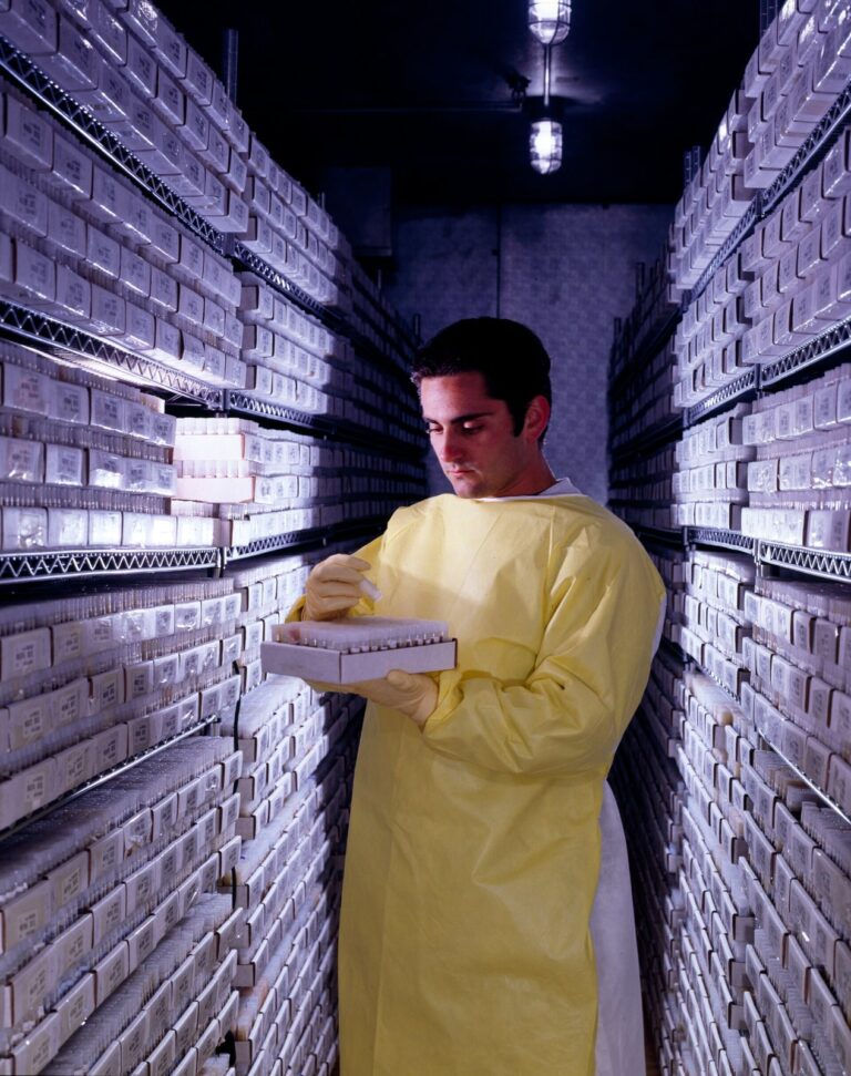 Pharmaceutical manufacturing technician inspecting production equipment in a GMP-compliant cleanroom facility