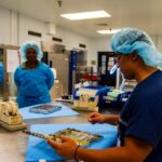 Sterile processing technicians inspecting a surgical instrument tray during medical device quality control
