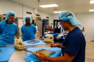 Sterile processing technicians inspecting a surgical instrument tray during medical device quality control