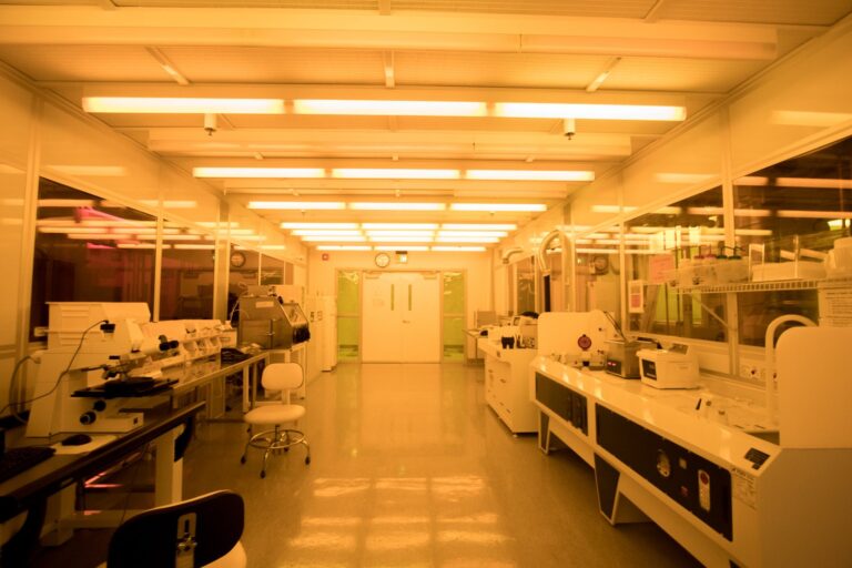Technician inspecting sterile precision components on a medical device cleanroom assembly line