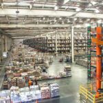 Consumer goods distribution center warehouse with stocked pallet racks, illustrating contract renewal risk in procurement