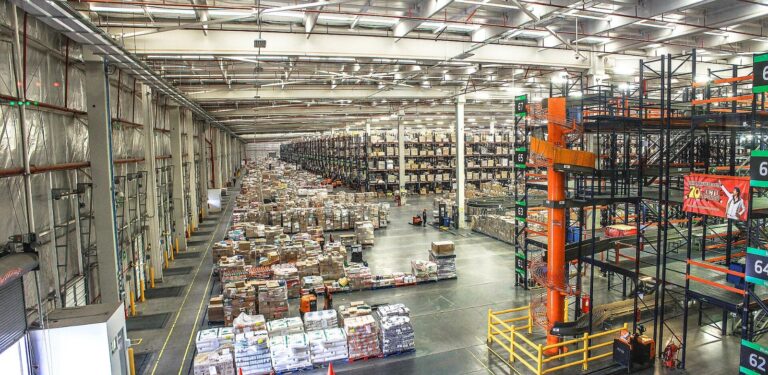 Consumer goods distribution center warehouse with stocked pallet racks, illustrating contract renewal risk in procurement