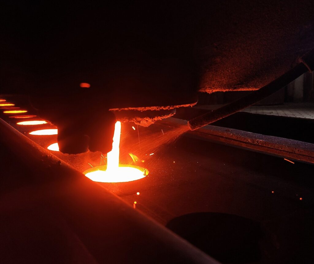 Molten cast iron poured into a sand mold at a metal foundry, illustrating signs a supplier is in financial trouble in industrial machinery sourcing